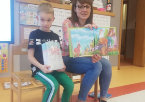 Wiktor z mamą pokazują ilustracje do czytanej bajki